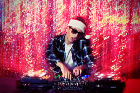 DJ man mixing up some Christmas cheer. Disco lights in the background. の写真素材
