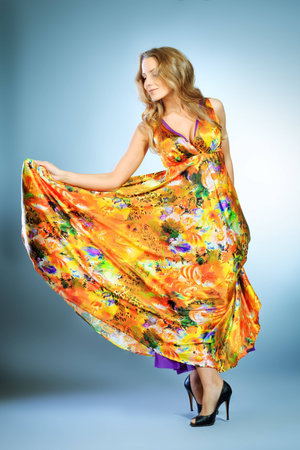 Charming young woman dancing in a vivid summer dress.の写真素材