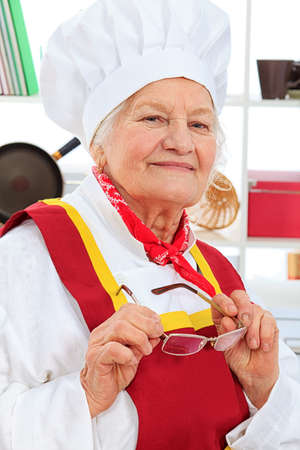 Portrait of a senior woman chef cook in the kitchen.の写真素材