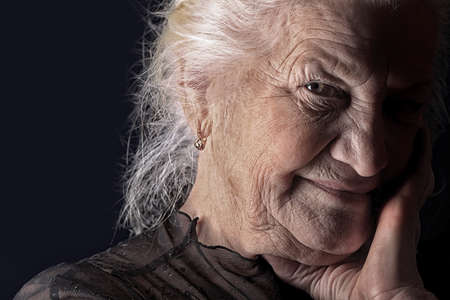 Portrait of a happy senior woman smiling at the camera. Over black background.の写真素材