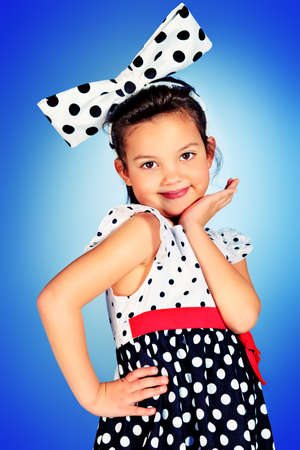 Portrait of a cute little pin-up girl in a beautiful dress and big bow. の写真素材