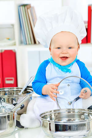 Cute small baby in the cook costume at the kitchen.の写真素材
