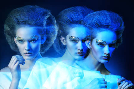 Art fashion photo of a beautiful model with golden make-up. Play of light and shadow.の写真素材