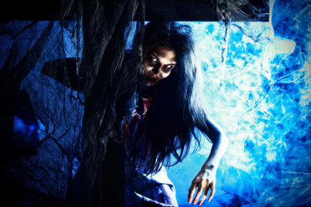 Bloodthirsty zombi standing at the night cemetery in the mist and moonlight.の写真素材