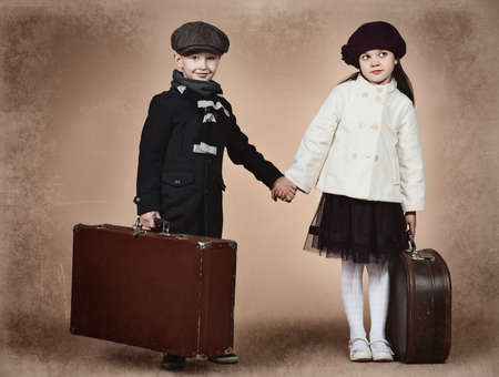 Cute little boy and girl are standing with their old suitcases. Retro style.の写真素材