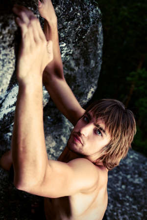 Young man alpinist is climbing on a mountain.の写真素材