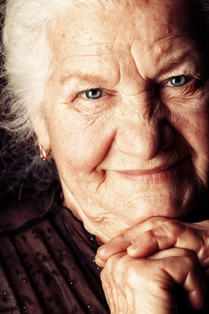 Portrait of a happy senior woman smiling at the camera. Over black background.