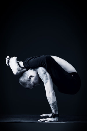Handsome man shows different yoga exercises over black background.
