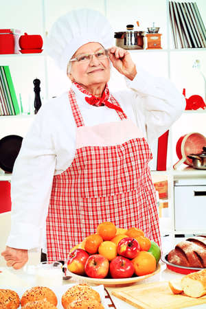 Senior woman chef cooks in the kitchen.の写真素材