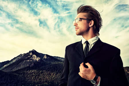 Successful business man standing on a peak of the mountain and purposefully looking away.の写真素材