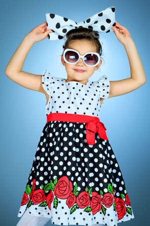 Portrait of a cute little pin-up girl in a beautiful dress and big bow. の写真素材