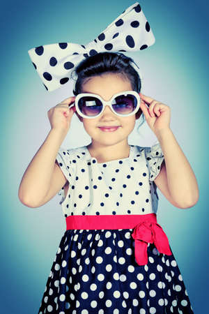 Portrait of a cute little pin-up girl in a beautiful dress and big bow. の写真素材