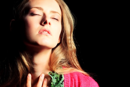 Portrait of a beautiful young woman in red blouse over dark background.の写真素材