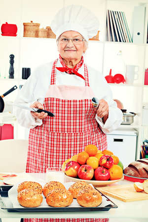 Senior woman chef cooks in the kitchen.の写真素材