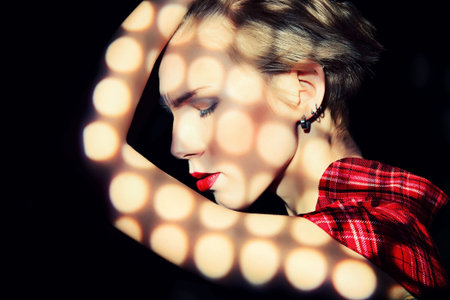 Portrait of a young fashionable model posing at studio with expression. Black background.