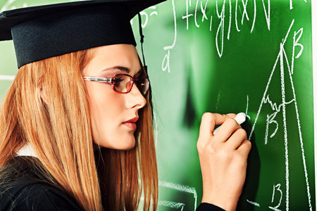 Graduating student girl in an academic gown standing at the classroom.
