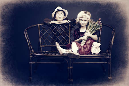 Cute little boy is giving bouquet of tulips to the charming little lady. Retro style.の写真素材