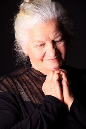 Portrait of a happy senior woman smiling at the camera. Over black background.