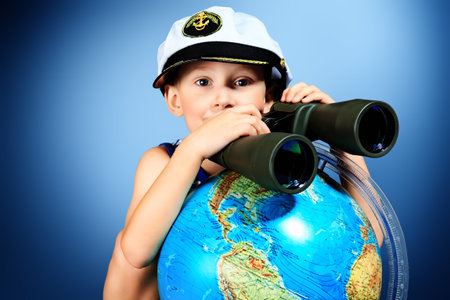 Little sailor boy sitting with the globe and binoculars.