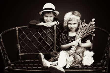 Cute little boy is giving bouquet of tulips to the charming little lady. Retro style.の写真素材