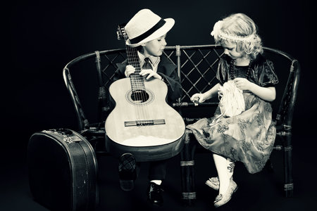 Cute little boy is playing the guitar to the charming little lady. Retro style.