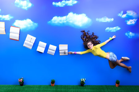 Happy girl student is flying in the sky after her books. の写真素材