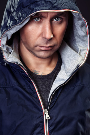 Handsome mature man in hooded jacket looking at camera.
