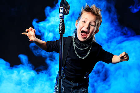 An emotional little boy is singing into a microphone like a rock musician. の写真素材