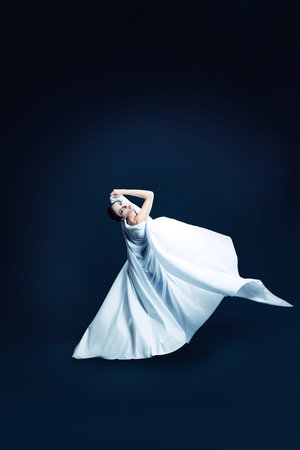 Art fashion photo of a beautiful woman dancing over black background.の写真素材