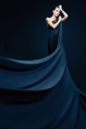 Art fashion photo of a beautiful woman in black dress. Over black background.の写真素材