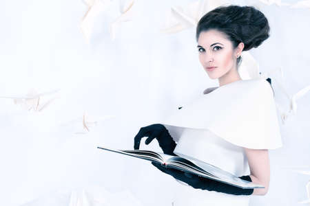Art fashion photo of a gorgeous woman in paper dress reading a book. Black and white.の写真素材