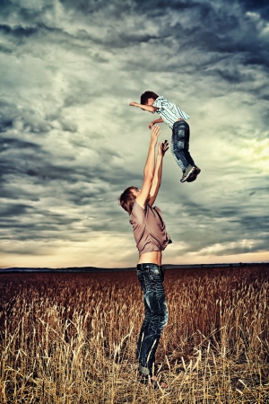 Happy father playing with his little son in the wheat field over beautiful cloudy sky. の写真素材