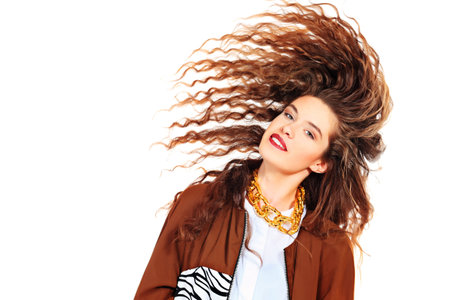 Charming fashion model with beautiful curly hair posing at studio. Isolated over white.