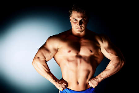 Portrait of a handsome muscular bodybuilder posing over black background.の写真素材