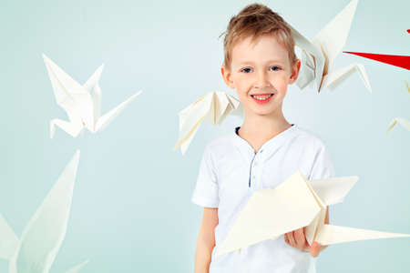 Happy little boy standing surrounded by paper birds. Dream world.の写真素材