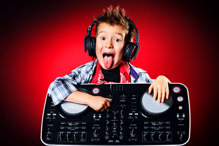 Expressive little boy DJ in headphones mixing up some party music.の写真素材