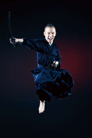 Handsome young man practicing kendo. Over dark background.の写真素材