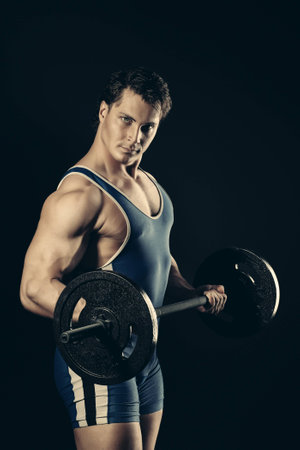 Portrait of a handsome bodybuilder posing over black background.の写真素材