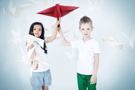 Happy kids standing together surrounded by paper birds. Dream world.の写真素材