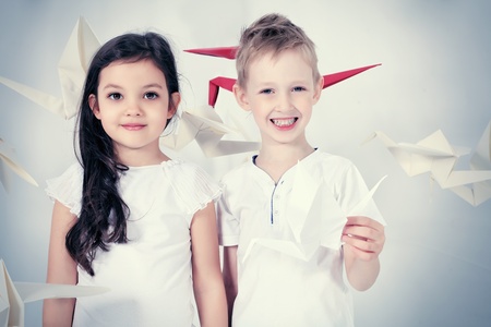 Happy kids standing together surrounded by paper birds. Dream world.の写真素材