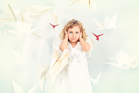 Beautiful little girl in her dream world surrounded with paper birds.の写真素材