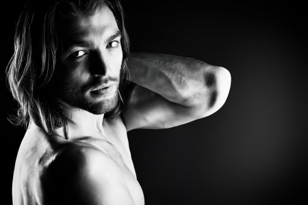 Portrait of a sexual muscular man posing over dark background.の写真素材