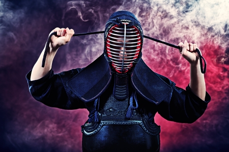 Handsome young man practicing kendo. Over dark background.の写真素材
