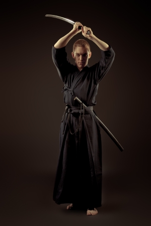 Handsome young man practicing kendo. Over dark background.の写真素材