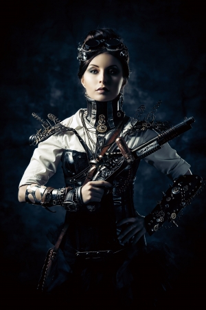 Portrait of a beautiful steampunk woman holding a gun over grunge background.の写真素材