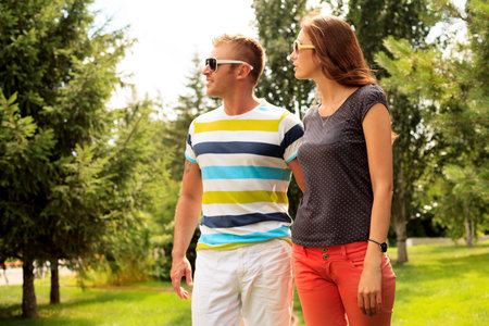 Beautiful happy couple walking in the park in sunny summer day.