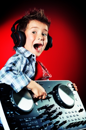 Expressive little boy DJ in headphones mixing up some party music.の写真素材