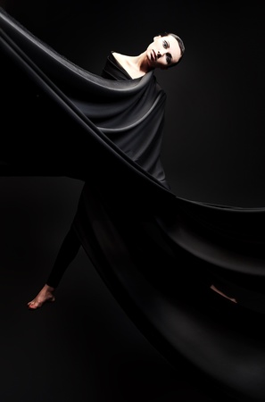Art fashion photo of a beautiful woman in black dress. Over black background.の写真素材