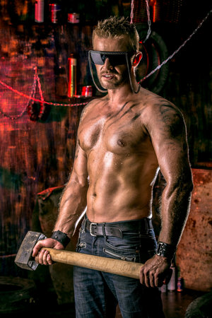 Handsome muscular man with sledgehammer working in the old garage.の写真素材