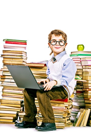A boy sitting on a pile of books with a laptop on his knees. Education. Isolated over white.の写真素材